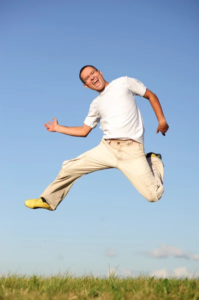 Человек прыгает по зеленому полю — стоковое фото