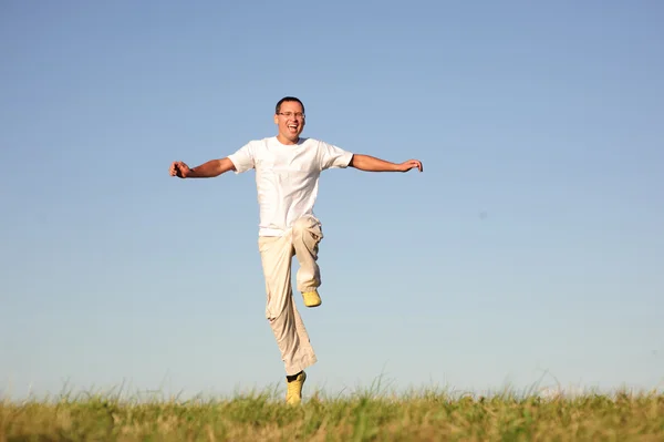 Homem pulando no campo verde — Fotografia de Stock