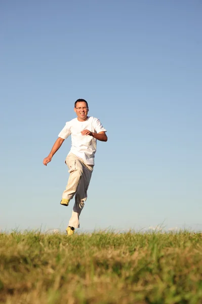 माणूस हिरव्या क्षेत्रात उडी — स्टॉक फोटो, इमेज