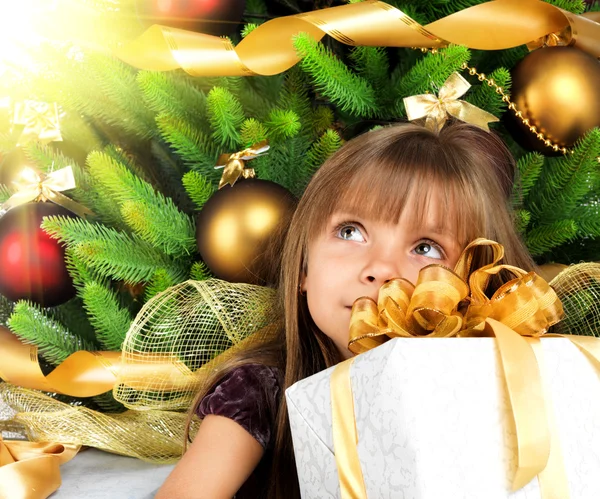 Chica bonita con presente cerca del árbol de Navidad — Foto de Stock
