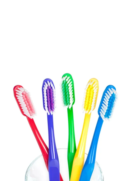 Kleurrijke tandenborstels in een glas water met — Stockfoto