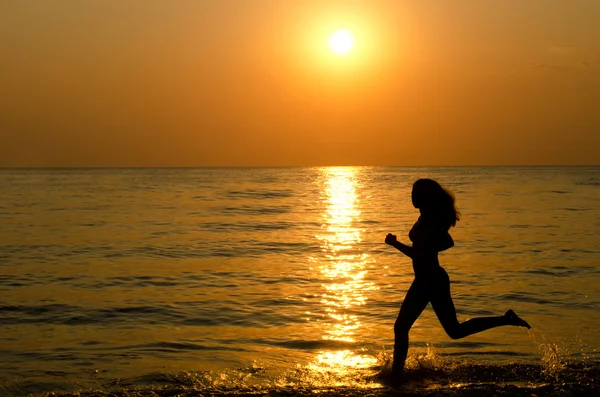 Vrouwelijke silhouet tegen een daling in de zee — Stockfoto