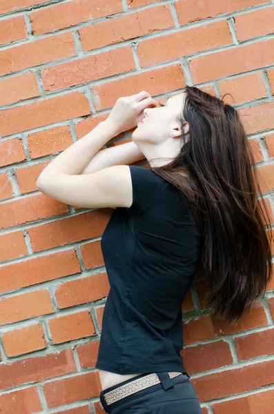 Молодая грустная девушка у кирпичных стен — стоковое фото