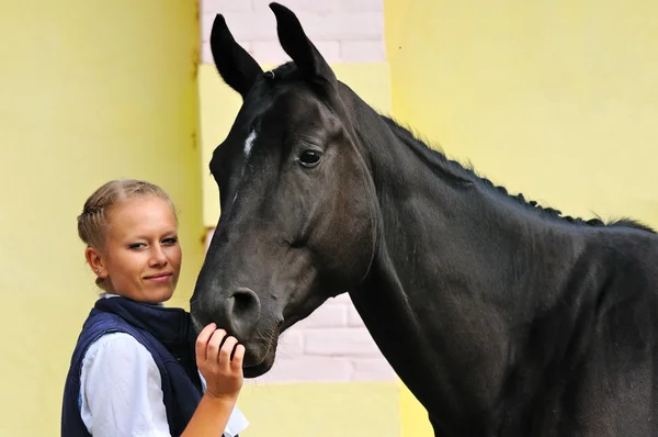 Девушка и черный спортивный конь перед соревнованиями — стоковое фото