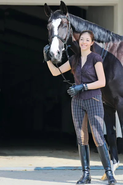 Молода дівчина з чорним спортивним конем — стокове фото
