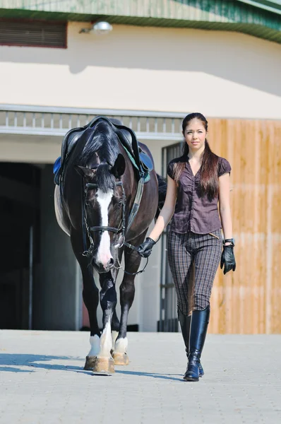 Mladá dívka na koni černé sportovní kůň — Stock fotografie