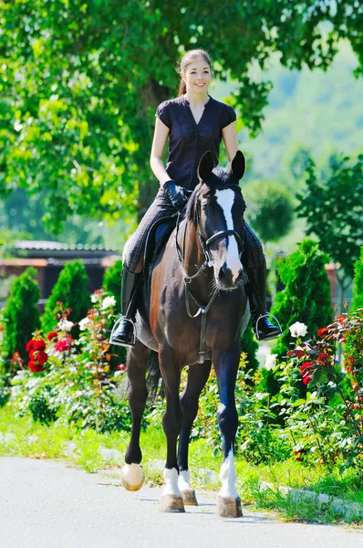 Young girl riding black sport horse — Stock Photo, Image