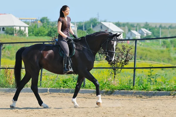 Mladá dívka na koni černé sportovní kůň — Stock fotografie