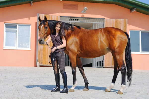 Jong meisje en baai paard — Stockfoto