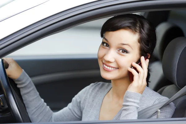 Happy young woman talk on cell phone sitting in white car — Stock Photo, Image