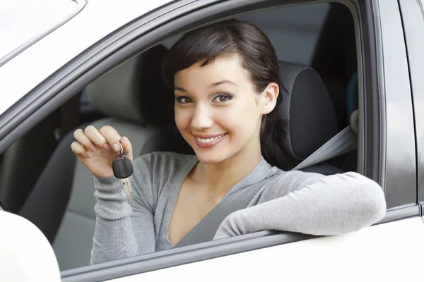 Menina bonita em um carro mostrando a chave — Fotografia de Stock