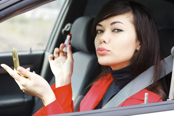Ganska kaukasisk kvinna i en bil som gör smink. — Stockfoto
