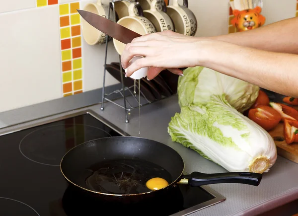 Femme craquant des œufs dans une poêle dans la cuisine — Photo