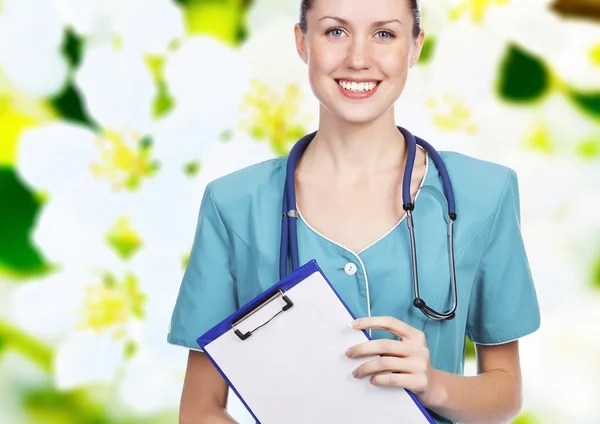 Улыбающаяся женщина-врач держит планшет против цветка backgro — стоковое фото
