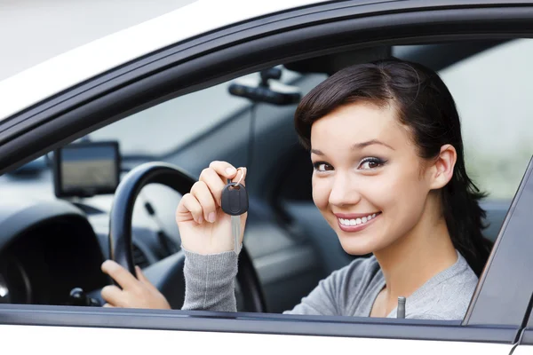Pretty asian female driver in a white car showing the car key — Stock Photo, Image