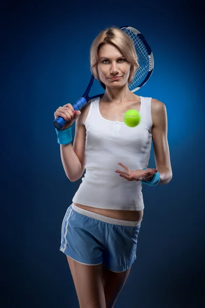 Mulher sorridente com uma bola de tênis e raquete em azul — Fotografia de Stock