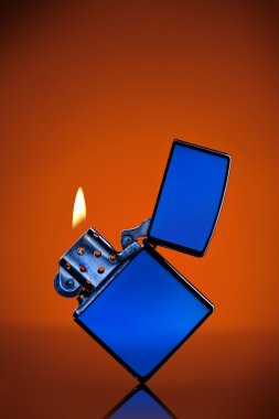 Blue zippo lighter with flame on orange background clipart