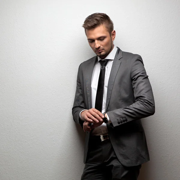 Hombre de negocios guapo mira su reloj en blanco —  Fotos de Stock