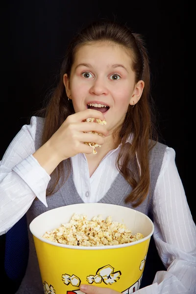 Chica sorprendida con palomitas de maíz sobre un fondo negro —  Fotos de Stock