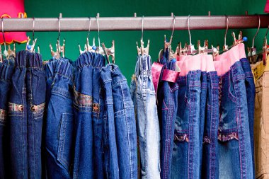 Denim pants on a hanger for children in the store clipart