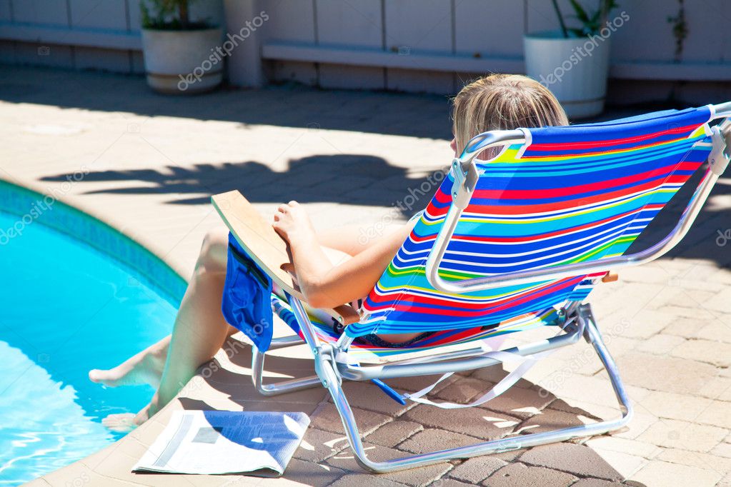 The woman is sitting near the pool