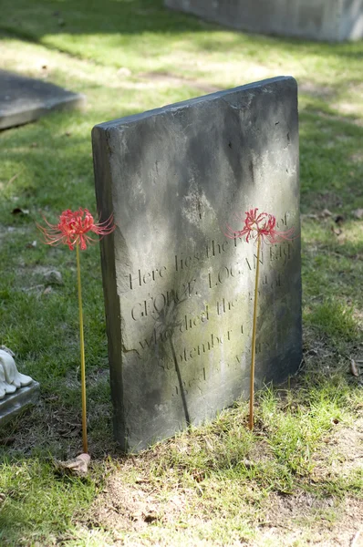 Oude grafsteen met bloemen — Stockfoto