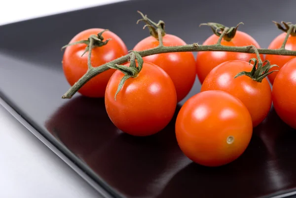 Cherry tomatoes in a black plate — Stock Photo, Image