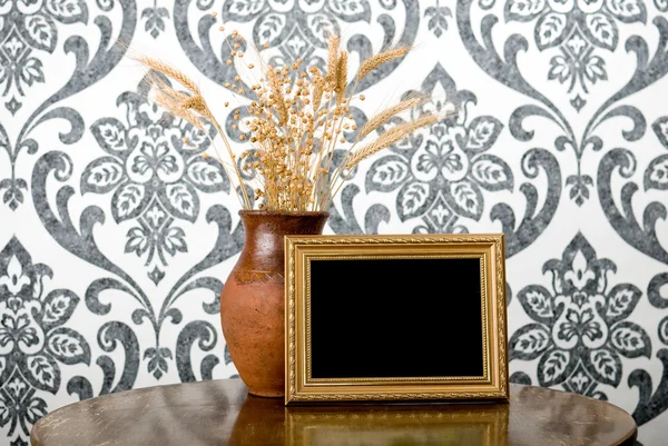 Golden photo frame and jug with wheat and flax on vintage table — Stock Photo, Image