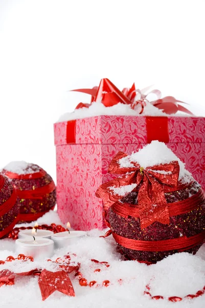 Caixa de presente de Natal na neve com bolas vermelhas e velas — Fotografia de Stock
