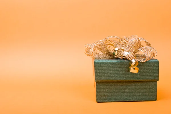 Одиночна зелена подарункова коробка з золотою стрічкою на жовтому фоні . — стокове фото