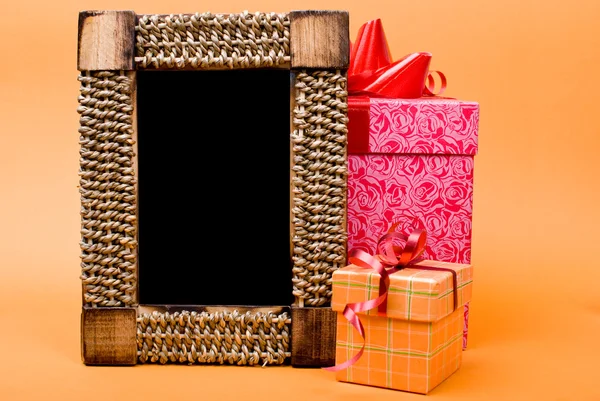 Фоторамка и подарочная коробка с лентой на оранжевом фоне . — стоковое фото