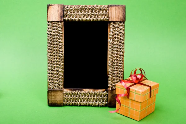 Foto moldura e caixa de presente com fita em fundo verde . — Fotografia de Stock