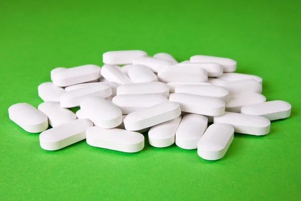 Píldoras médicas sobre el fondo verde — Foto de Stock