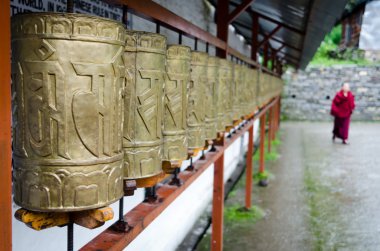 Buddhist monk and prayer wheels in a row clipart