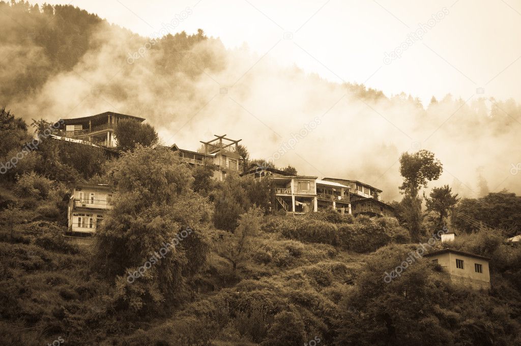 Houses in mountains covered by clouds and rain