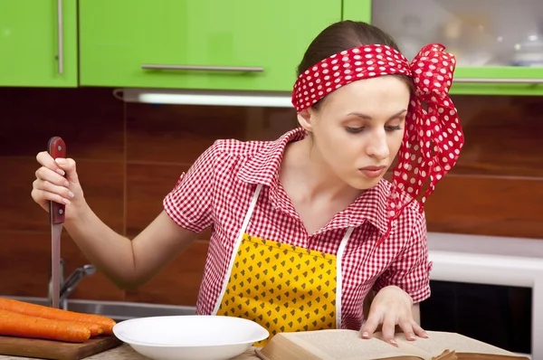 Mulher na cozinha com livro de receitas faca — Fotografia de Stock
