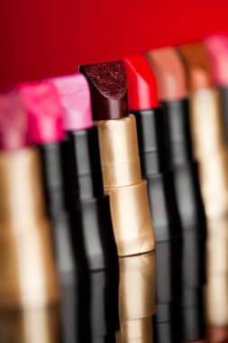 Many lipsticks on red background (shallow DOF) clipart