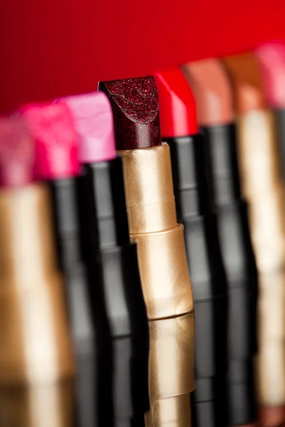 Viele Lippenstifte auf rotem Hintergrund (flach dof) — Stockfoto