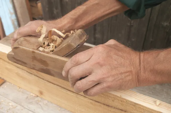 Mãos de um carpinteiro de madeira aplainada — Fotografia de Stock
