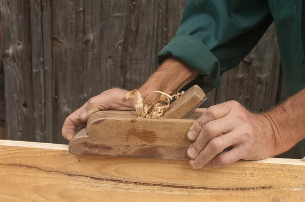 Mãos de um carpinteiro de madeira aplainada — Fotografia de Stock