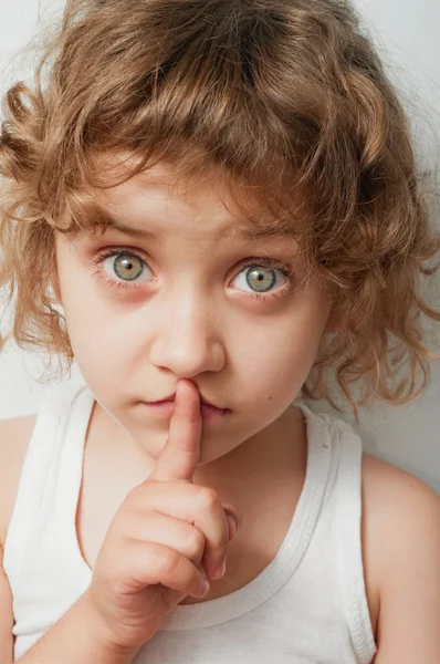 Kleines Mädchen hält Finger auf Lippen — Stockfoto