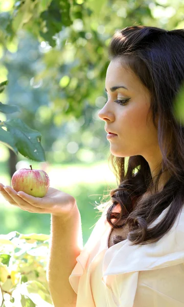 Roztomilá mladá žena drží jablko v ruce proti pozadí — Stock fotografie