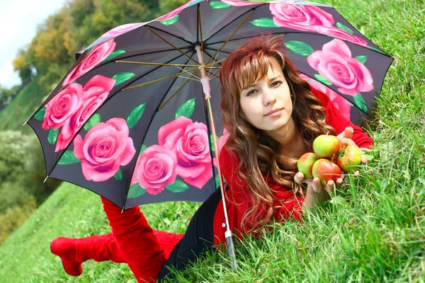 Menina lindo em vestido vermelho e botas deitado com maçãs safadas sob um — Fotografia de Stock