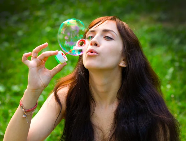 Portrait de jeune fille attrayante gonflant des bulles de savon colorées en plein air — Photo