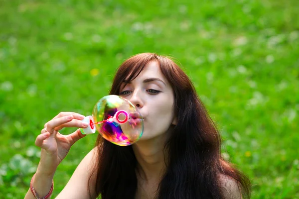 Retrato da menina atrativa que infla bolhas coloridas do sabão exterior — Fotografia de Stock