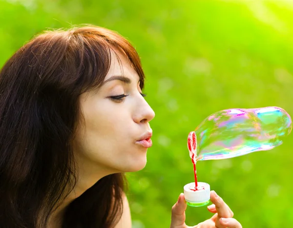Портрет привабливої молодої дівчини, що надуває різнокольорову мильну бульбашку — стокове фото