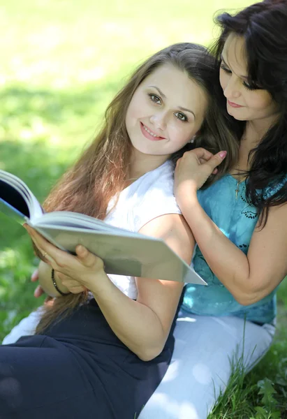 Beautiful mother and daughter reading fairy book in summer park — Stock Photo, Image
