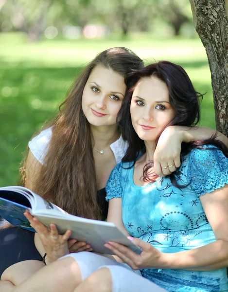 Красива мати і дочка читають казкову книгу в літньому парку — стокове фото