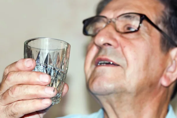 Портрет пожилого человека, поющего со стаканом водки — стоковое фото