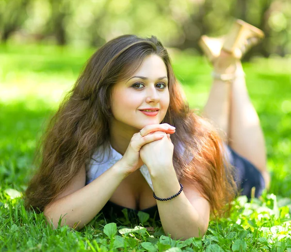 Sinnliches junges brünettes Mädchen liegt im Sommerpark — Stockfoto